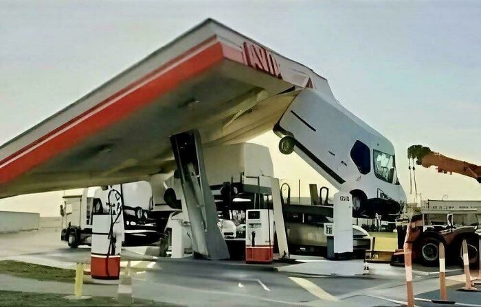 A large truck oddly parked vertically inside a gas station canopy, showcasing a major parking fail shared online.