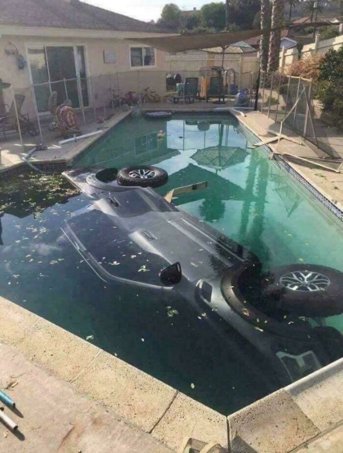 Car submerged upside down in a residential swimming pool, showcasing a major parking fail mishap outdoors.