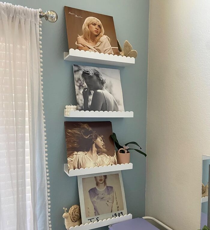 White scalloped wall shelves holding framed pictures and small decor, showcasing sneakily useful decor items in a bedroom corner.