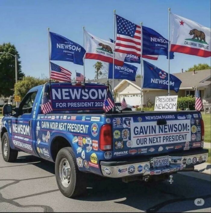 Pickup truck covered with Gavin Newsom campaign stickers and flags promoting chaotic good political support.
