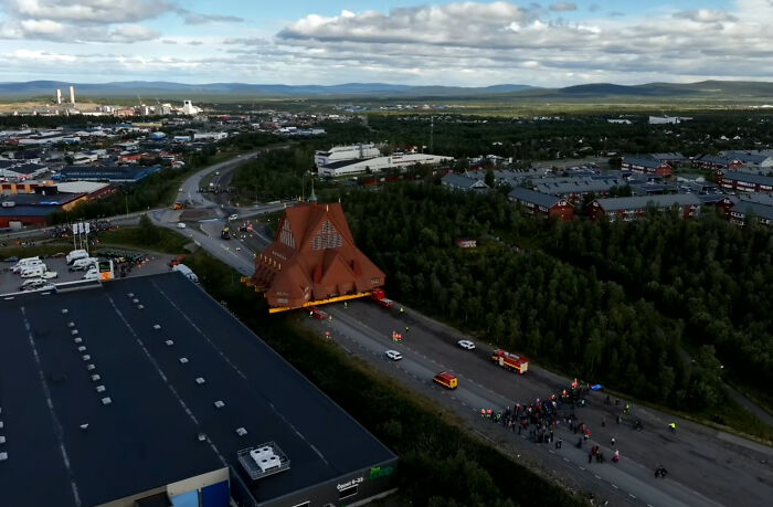 An extremely large church building being moved on a highway, appearing scary and eerie due to its massive scale.