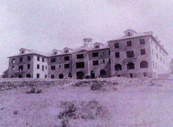 Old abandoned building with broken windows in a desolate area, capturing a creepy and unsettling moment.