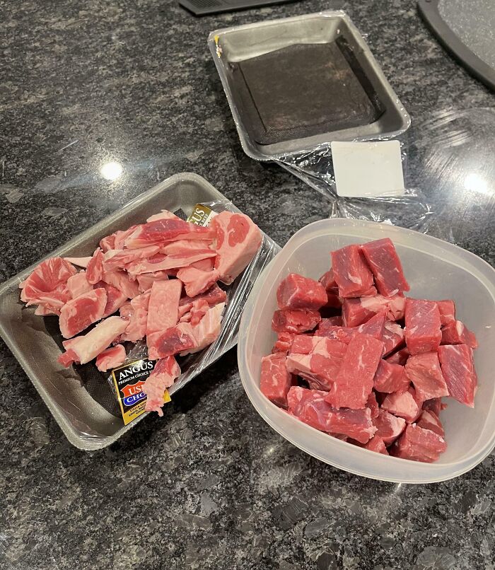Raw chopped beef meat pieces in plastic containers on a kitchen countertop showing sibling shenanigans.