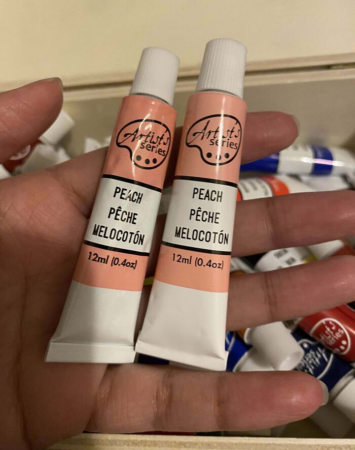 Two tubes of peach-colored artist series paint held in a hand, showcasing sibling shenanigans with identical items.
