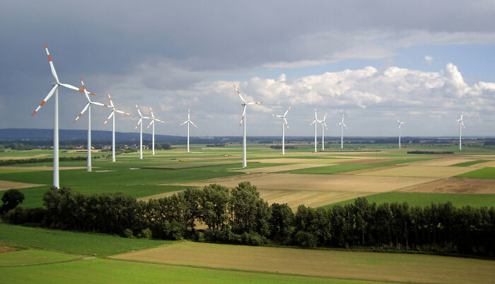 Wind turbines in a vast green field showcasing brilliant infrastructure for sustainable energy production under a partly cloudy sky