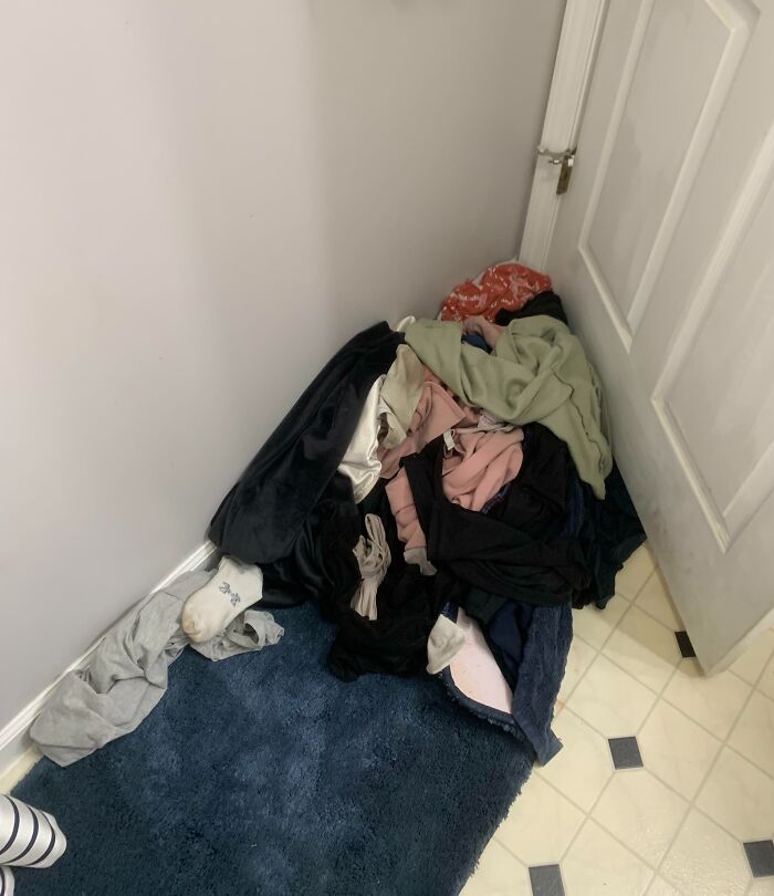 Pile of clothes in a corner with a hidden sibling among the shenanigans, highlighting sibling prank moments.