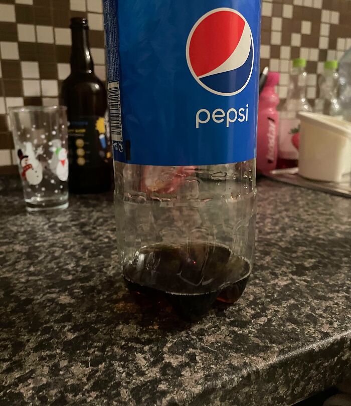 Half-empty Pepsi bottle on a kitchen counter with various items in the background, illustrating sibling shenanigans.