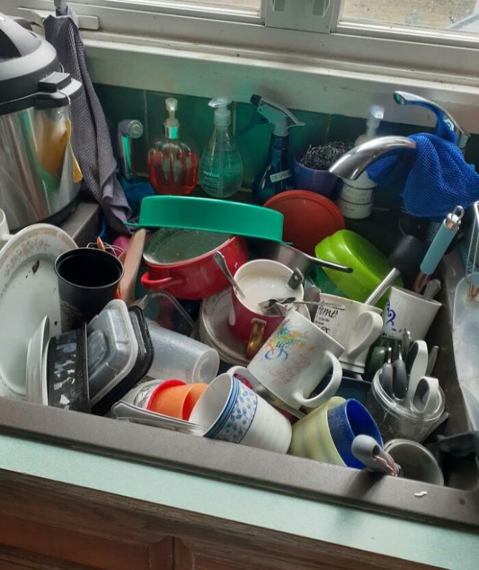 Lavaplatos lleno de trastes sucios acumulados, mostrando el desorden típico con un hermano consentido en casa.