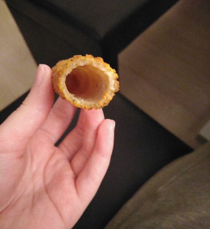 Hand holding a hollow fried snack, highlighting quirks shared by people who wish they didn’t have a sibling.