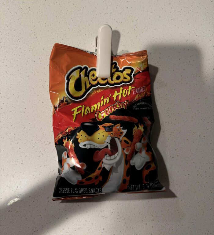 Flamin Hot Cheetos bag clipped with a white clip on a speckled white countertop, snack photo shenanigans.