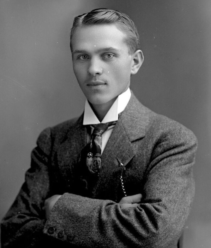 Victorian handsome man in a classic suit with folded arms, showcasing vintage style from the Victorian era.