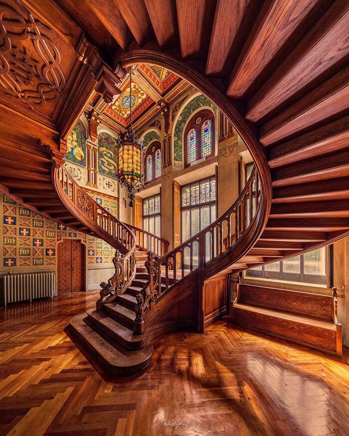 Ornate wooden spiral staircase and richly decorated interior, exemplifying beautiful old-world architecture.