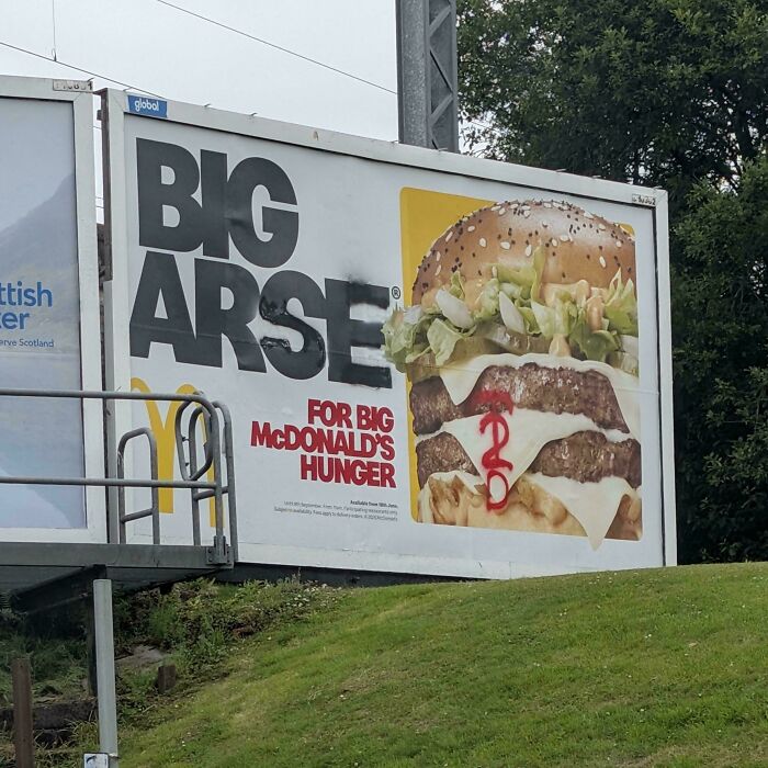 Billboard with witty graffiti altering McDonald's ad, showcasing clever humor capturing attention in a public space.