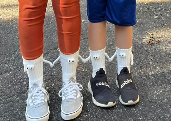 Matching white socks with googly eyes worn with sneakers on pavement, showcasing fun impulse buys fashion accessory.