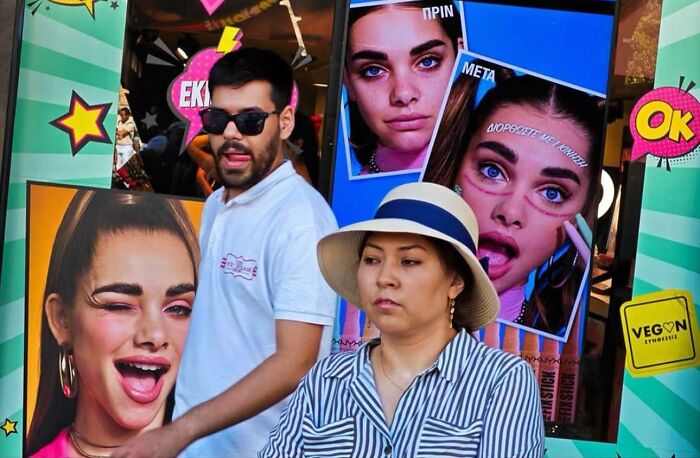 Street photo capturing the beauty of everyday life with diverse people in front of colorful vibrant advertisement displays.