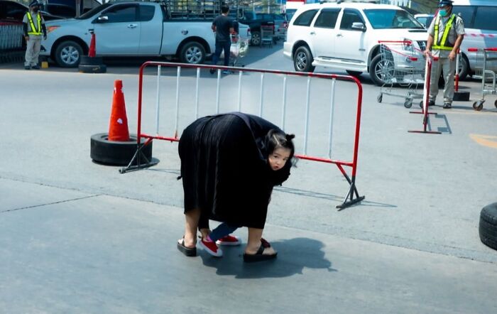 Street photo capturing a woman bending to tie child’s shoes, revealing the beauty of everyday life in an urban setting.