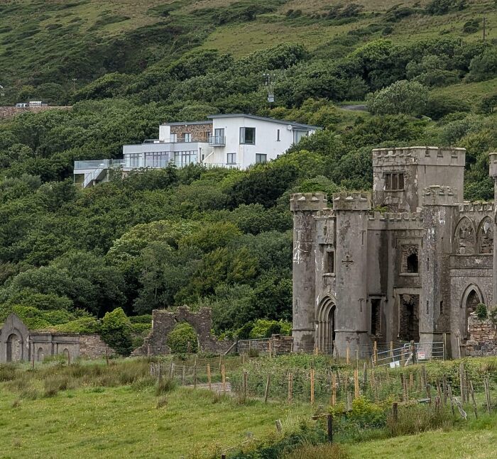 Old stone castle ruins near a modern house surrounded by lush green hills in a scenic comparison setting.