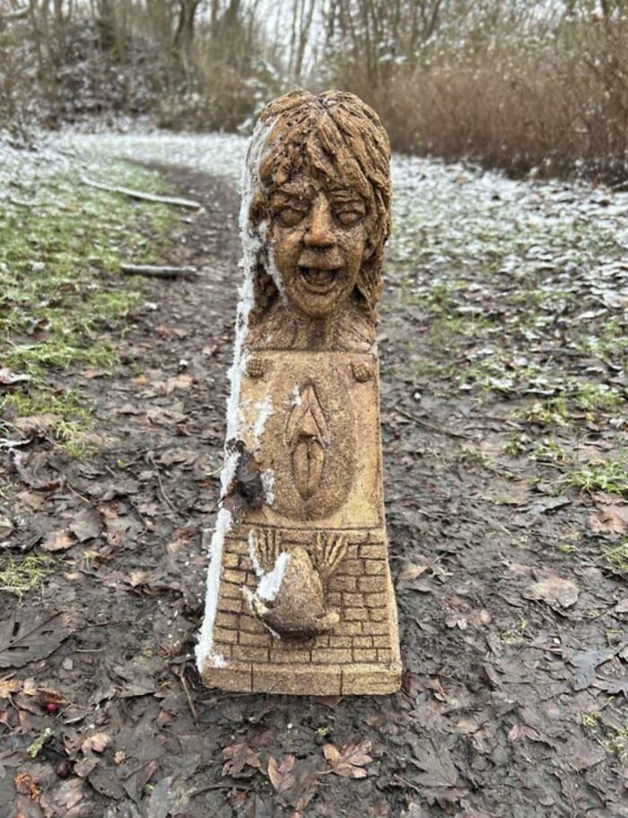 Carved wooden sculpture with a screaming face on a snowy forest path, capturing a creepy and unsettling moment.