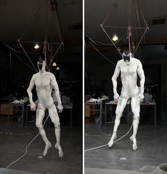 Creepy and unsettling humanoid figure suspended by wires in a dimly lit workshop, creating eerie atmosphere.