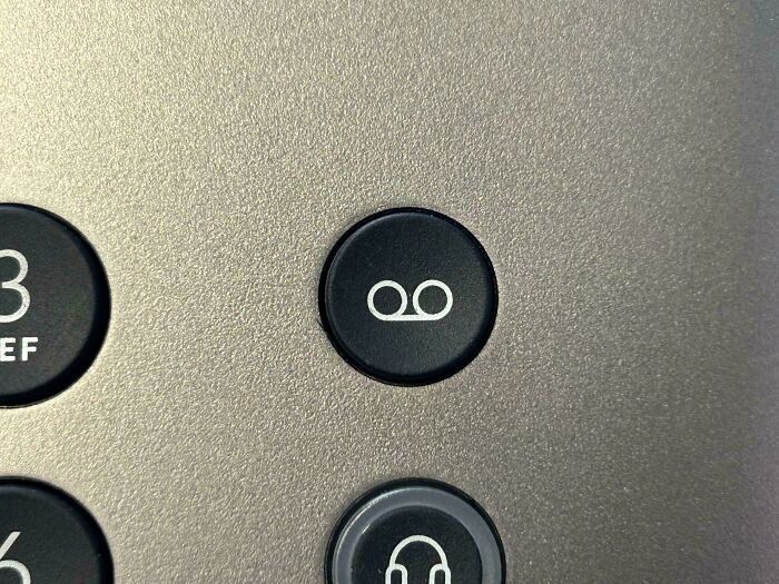 Close-up of an old answering machine button symbol on a nostalgic vintage telephone keypad.