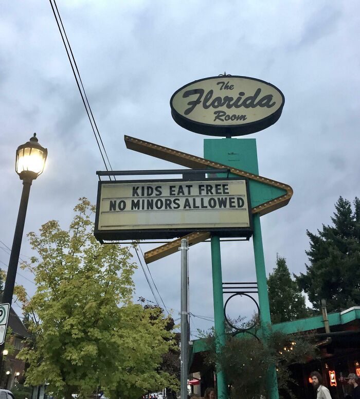 Vintage sign at The Florida Room that reads kids eat free no minors allowed, showcasing witty humor in public signage.