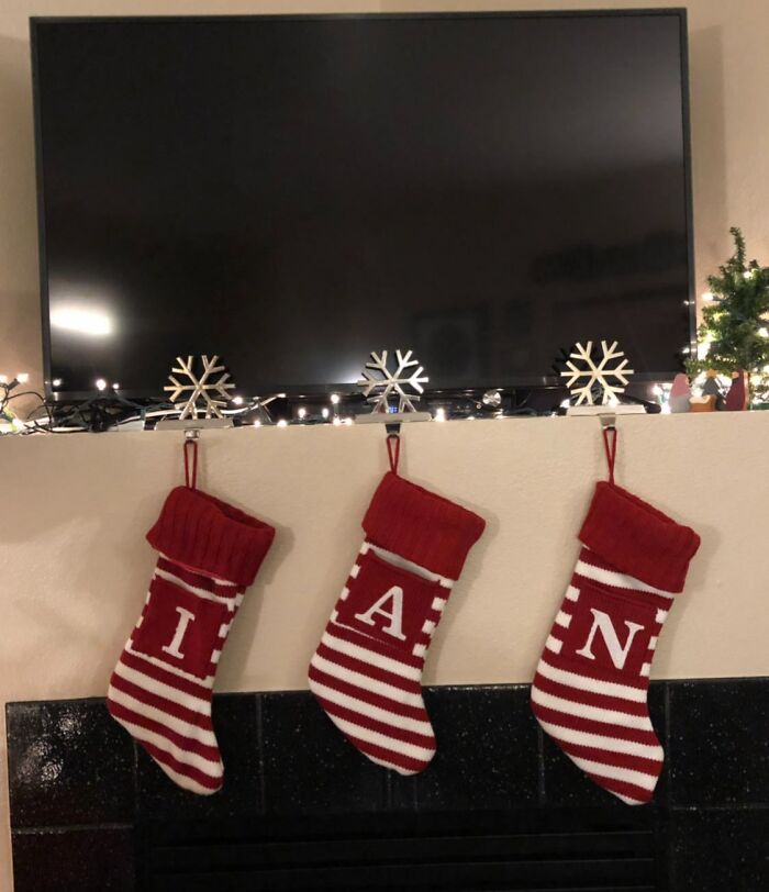 Three red and white striped Christmas stockings hanging wit the letters I, A, and N spelling a witty holiday message.