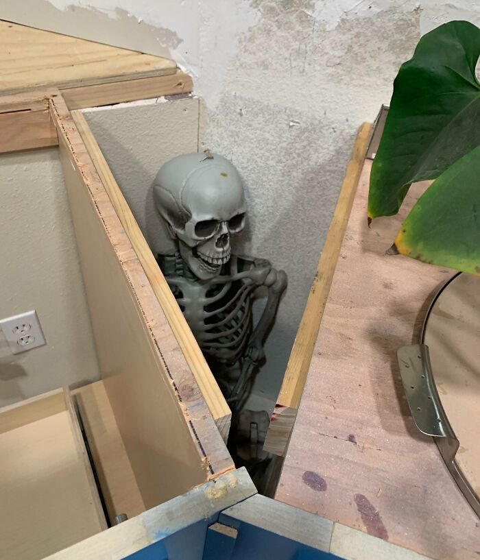 Skeleton hidden in a corner prank showing witty humor and clever placement in a cluttered indoor space.
