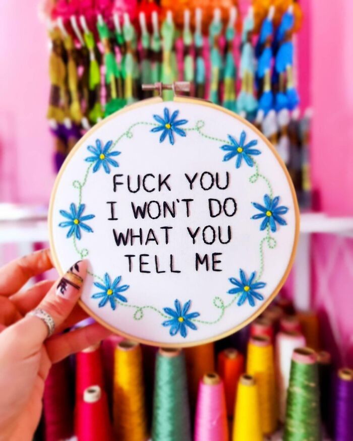 Hand holding embroidery hoop with bold text and blue flowers, showcasing incredible and beautiful embroidery skills.