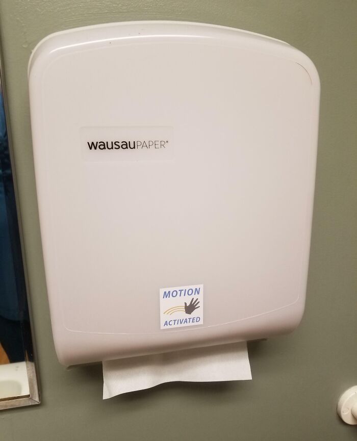 White paper towel dispenser labeled motion activated with a hand symbol, showcasing witty humor in public restrooms.