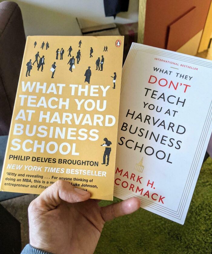 Hand holding two Harvard Business School books, showing witty and insightful cover titles about business lessons and knowledge.