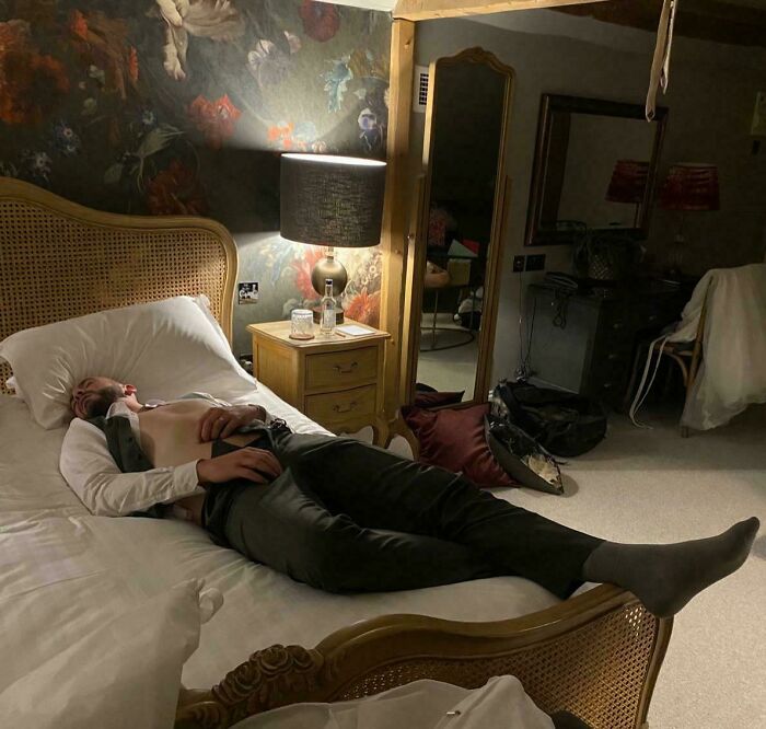Man lying on a bed in a vintage room with floral wallpaper, captured in a captivating accidental Renaissance photo.