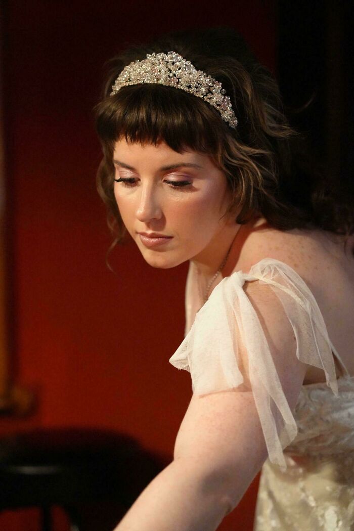 Woman with jeweled headband and sheer off-shoulder dress in a soft light, creating an accidental Renaissance photo effect.