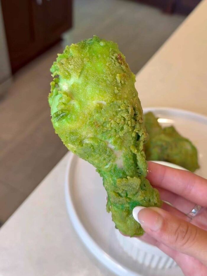 Hand holding a green fried chicken drumstick, one of the unusual dishes from 102 dishes that are just stupid.