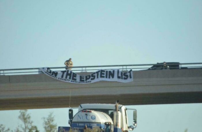 Person attempting to hang a large banner on a highway bridge, showcasing one of the times there was an attempt gone differently.