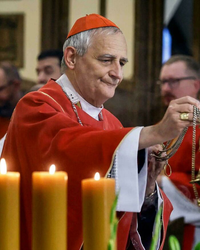 Clergyman in red robes performing a ritual with incense in a dimly lit room, capturing a moment of modern life.