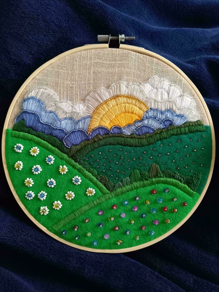 Stunning embroidery creation depicting a sunrise over rolling hills with flowers, inspiring new hobby.