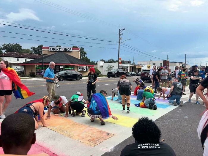 People creating a colorful street chalk mural, expressing chaotic good values through creative public activism.