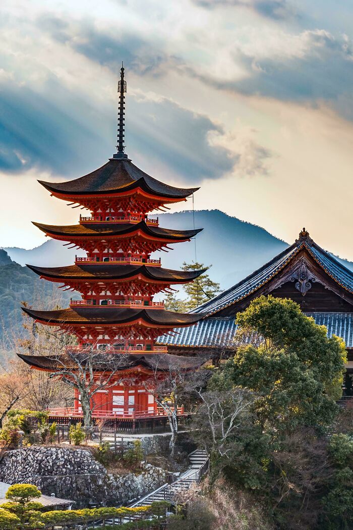 Stunning Japanese pagoda architecture with vibrant red tiers against a mountain backdrop, showcasing beautiful design.