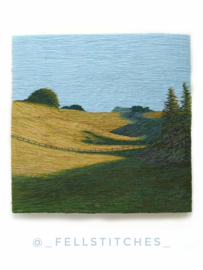 A beautiful embroidery creation depicting a rolling green and golden landscape under a light blue sky.