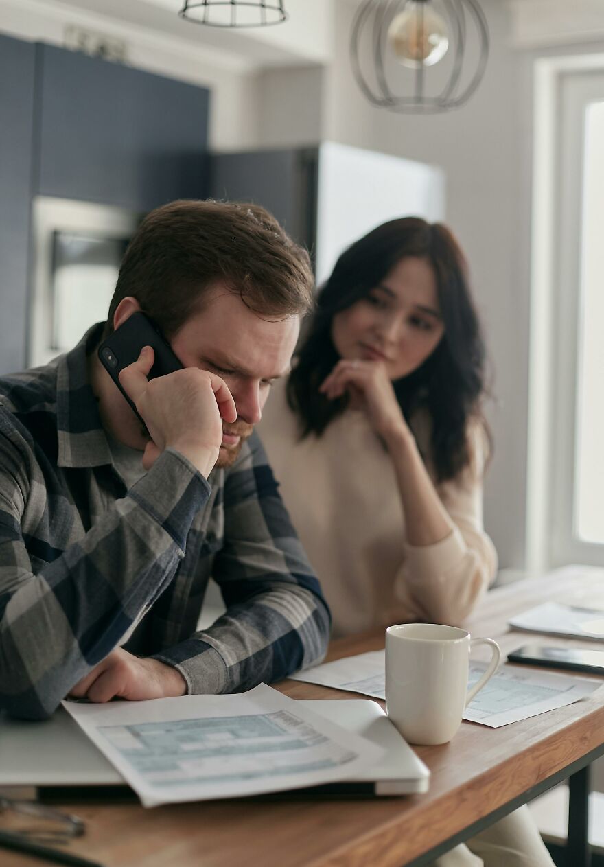 Man on phone looking stressed while woman watches him, illustrating unsettling signs of soul ties affecting relationships.