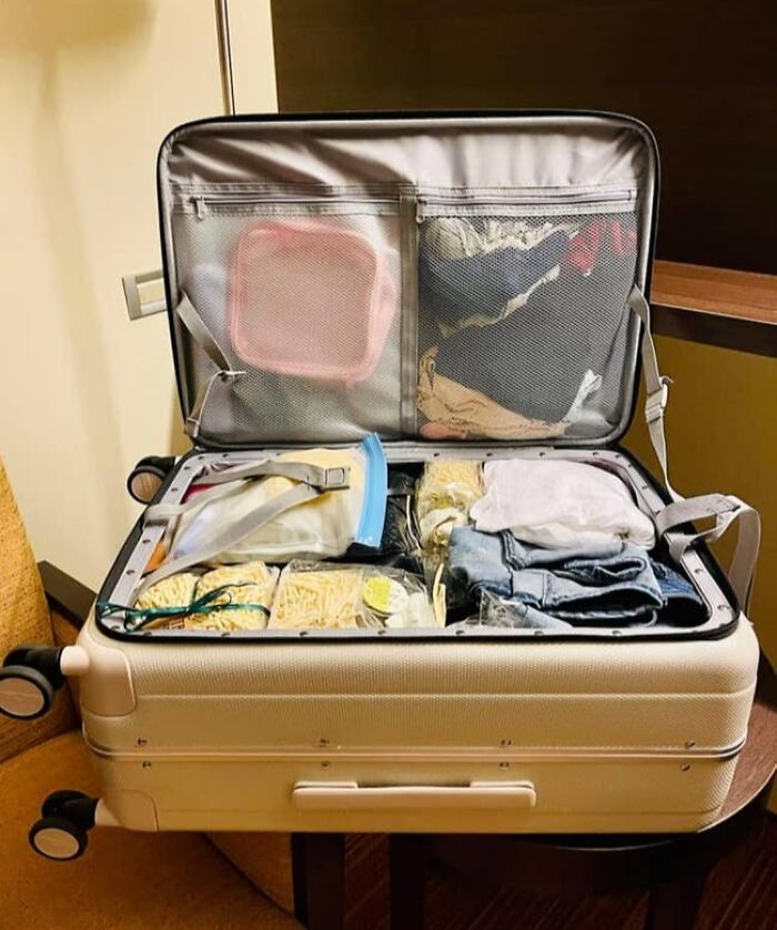 Open suitcase neatly packed with clothes and travel essentials organized in clear bags for efficient travel packing.