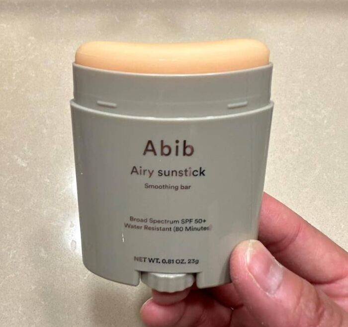 Hand holding Abib airy sunstick SPF 50+ sunscreen, a travel find for people bad at packing for trips.
