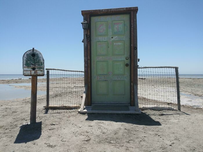 Old green door and mailbox fenced on a sandy beach, showcasing bizarre things people found at the beach.