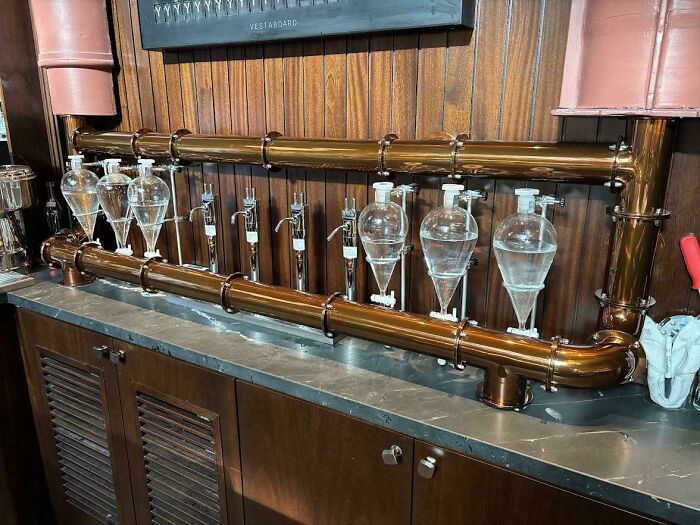 Unique bar setup with glass vessels and brass pipes showcasing creative design in bars and restaurants worldwide.