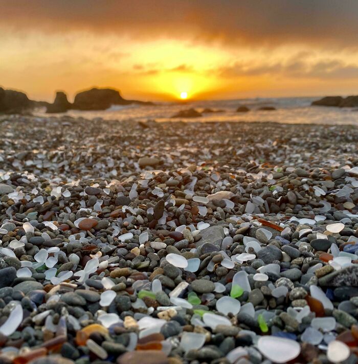 Close-up of colorful sea glass and pebbles on a beach at sunset, showcasing interesting and bizarre things found at the beach.