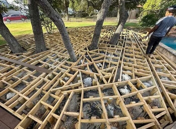 Wooden framework for a deck built around trees showing a DIY disaster with poor planning and construction mistakes.