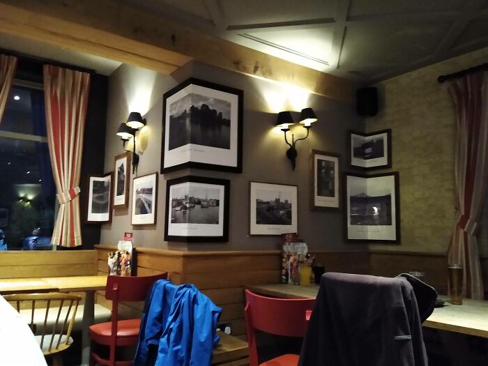 Cozy bar and restaurant interior with creative decor and framed photos, featuring warm lighting and colorful chairs.