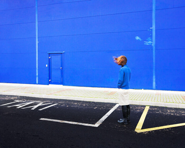 Person wearing a blue sweater standing against a vibrant blue wall, blending with their surroundings in a striking way.