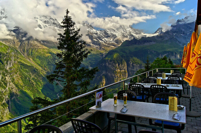 Outdoor seating at a creative bar with mountain views, showcasing unique design and stunning landscapes worldwide.
