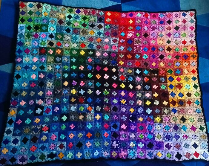 Colorful crocheted blanket made of small granny square motifs showcasing mastered crocheting art in vibrant patterns.